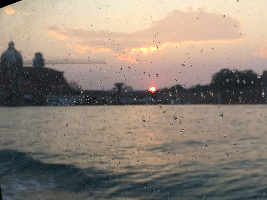 Sonnenuntergang über Venedig, durch gischtbespritzte Fenster des Vaporetto hinaus. Ein Glutball, der hinter den Palazzi versinkt. Wunderschön!