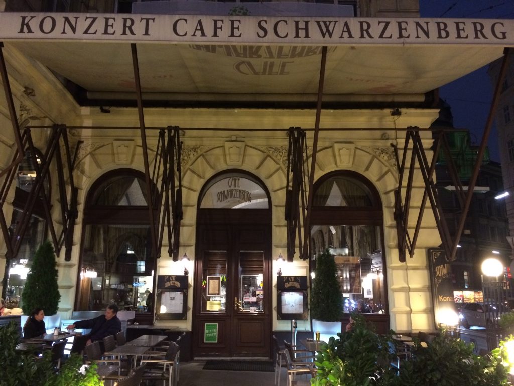 Außenansicht des Café Schwarzenberg mit Schanigarten (Biergarten) davor und riesiger Markise darüber.