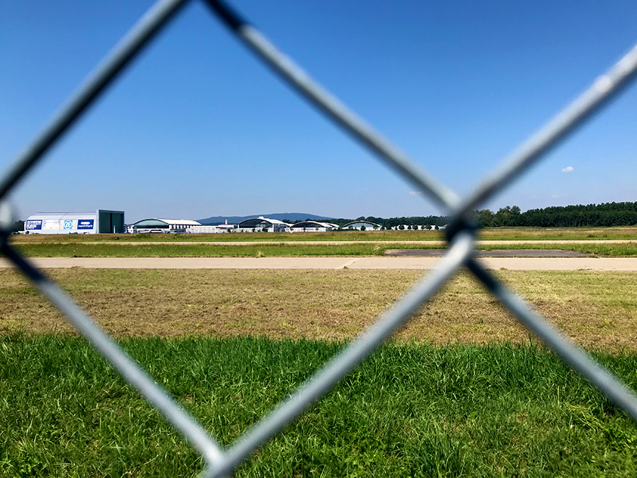 Blick durch den Zaun zum gegenüberliegenden Hangar des Flugplatzes von Friedrichshafen.