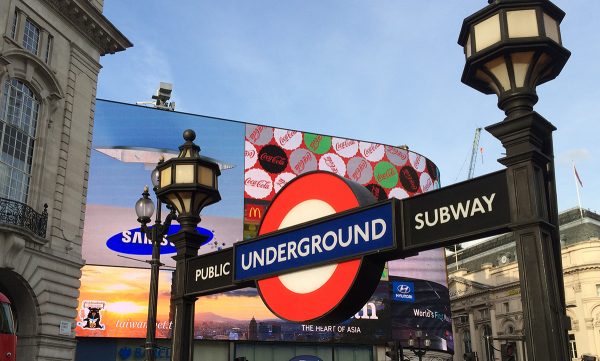 Das typische Londoner Underground-Zeichen, roter Ring mit blauem Balken, hier am berühmten Piccadilly Circus.