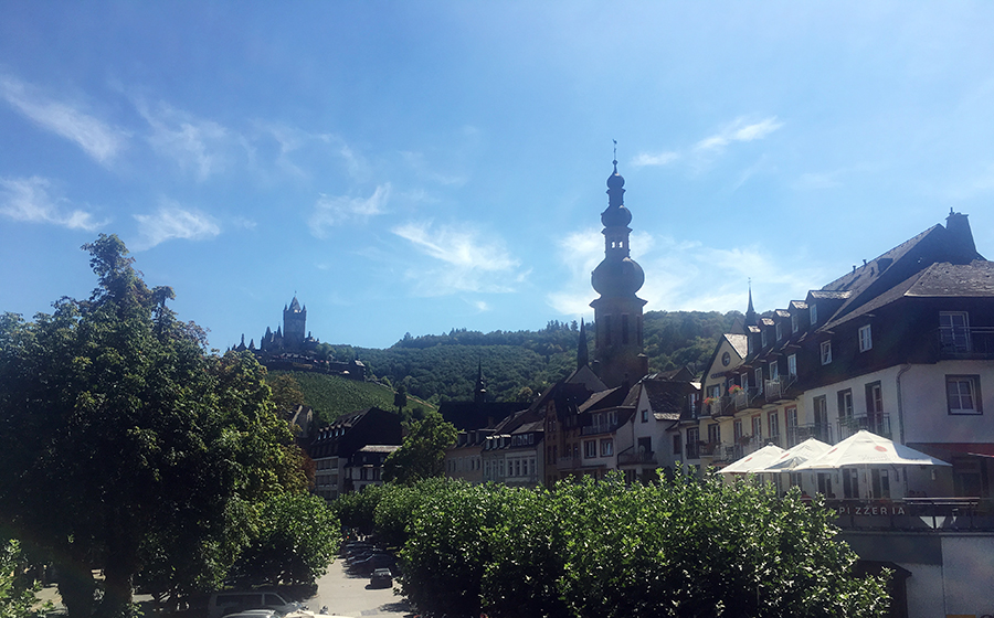 Die schönen Häuser an einer Allee in Cochem am Moselufer und im Hintergrund die Reichsburg.