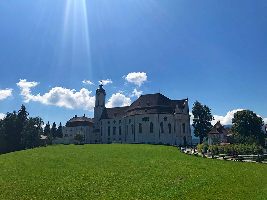 Auf einer kleinen Anhöhe, nur wenige Schritte vom Parkplatz entfernt, liegt sie: Die Wieskirche in Steingaden.