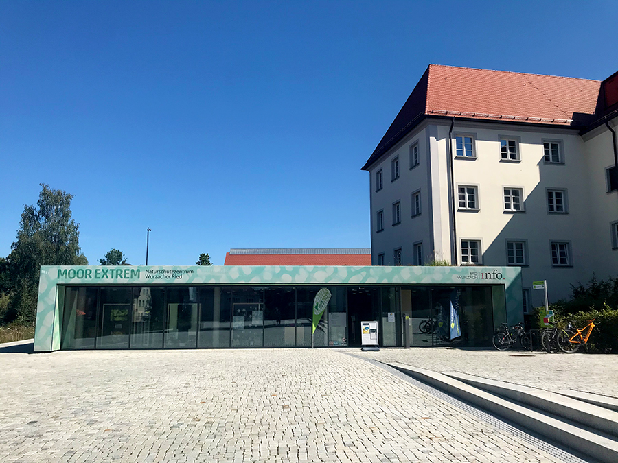 Zwischen der Kirche St. Verena und dem Eingang zum Kurpark liegt die Touristeninfo von Bad Wurzach sowie das Infozentrum 'Moor Extrem'.