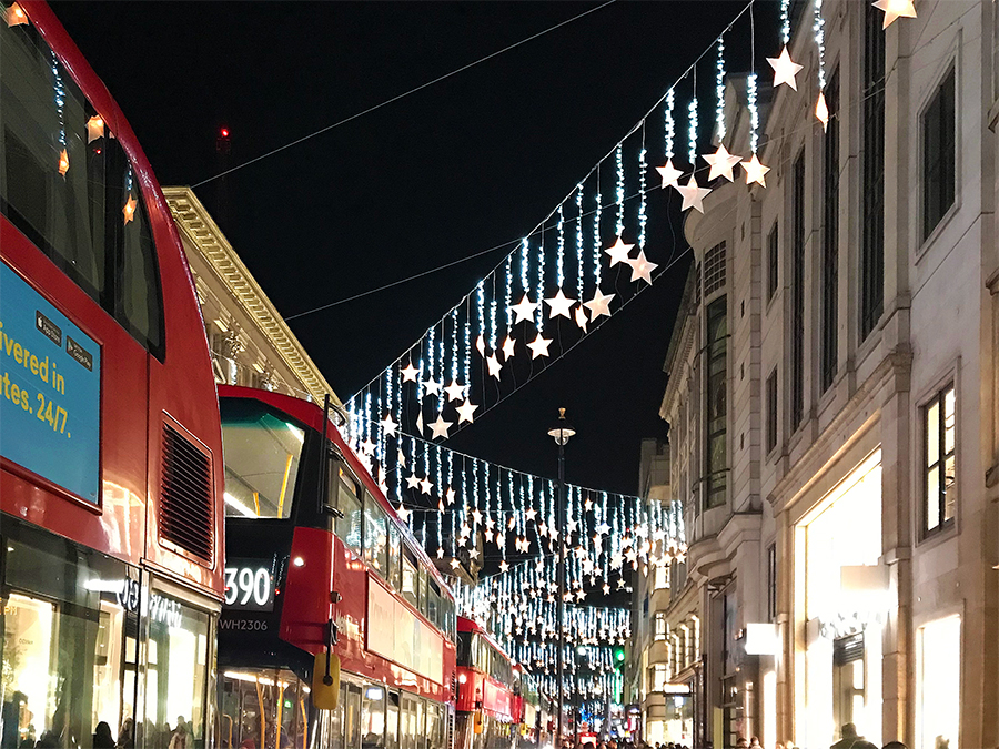 Eine klassische Reihe roter Doppeldeckerbusse unter der Weihnachtsdekoration der Oxford Street in London.