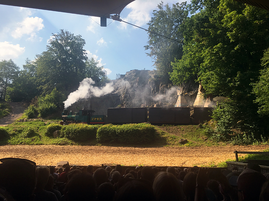 ... eine richtige Dampf-Eisenbahn fährt auf Schienen über die Bühne...